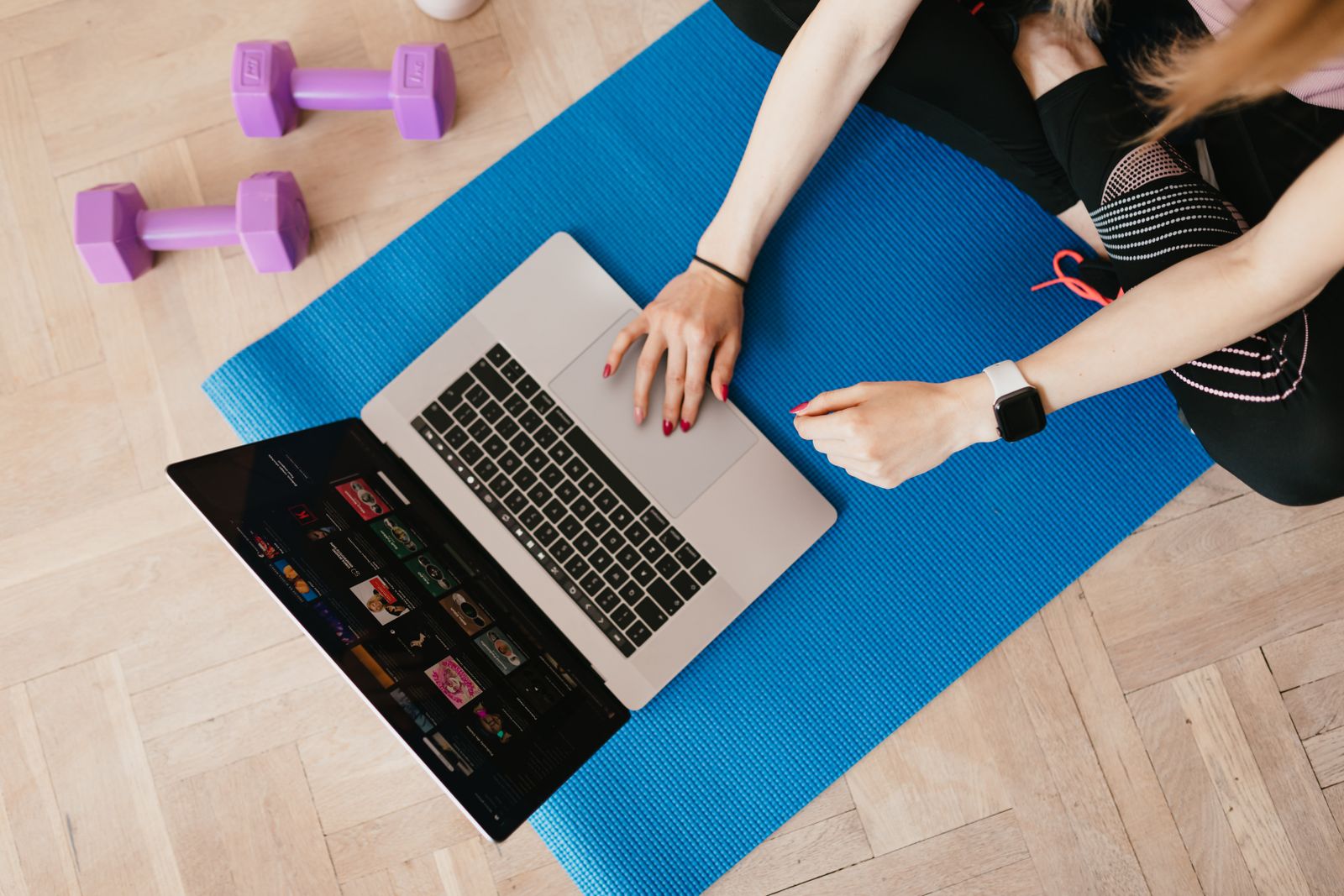 Overhead view of a laptop with a video library on screen, resting on a yoga mat